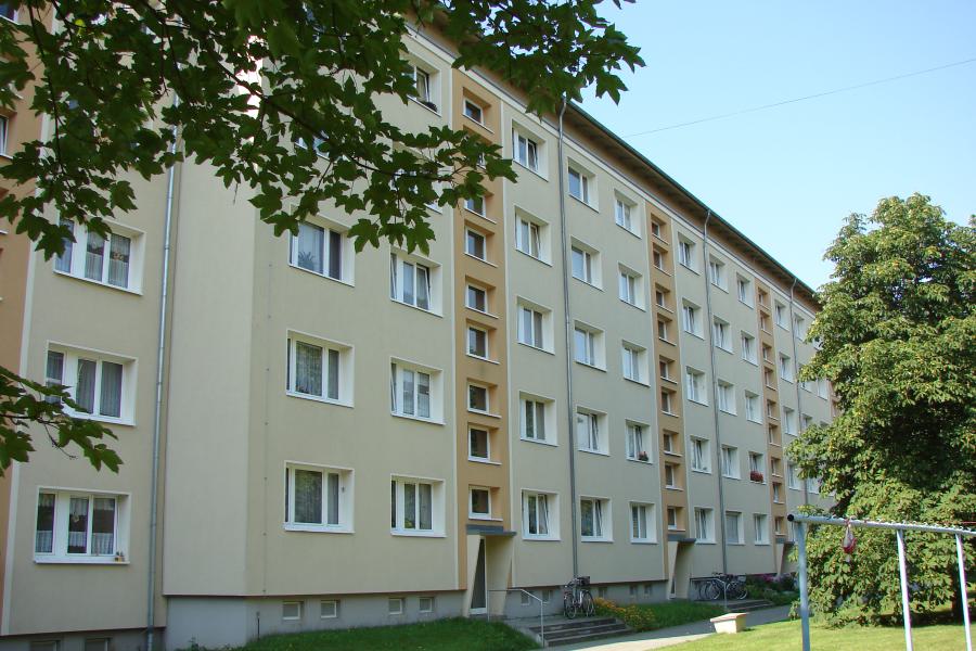 Mehrstöckiges Wohngebäude mit  Grünfläche und Wäscheplatz davor.